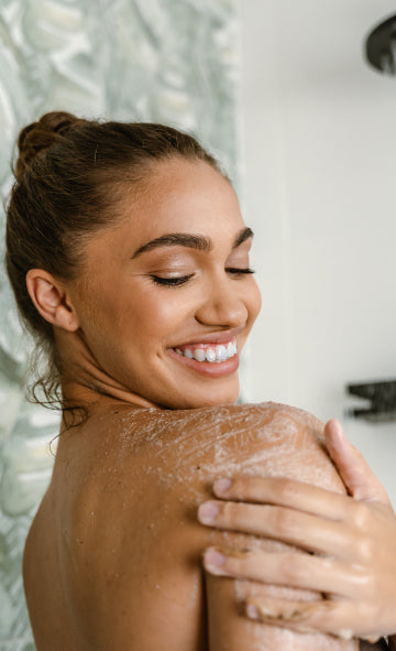 Woman with soap suds on her back in a shower setting